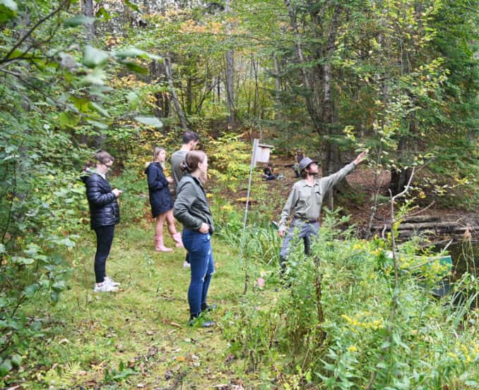 A group of Biology and Environmental Science students accompany their professor in the local woods as they learn about identifying various plants