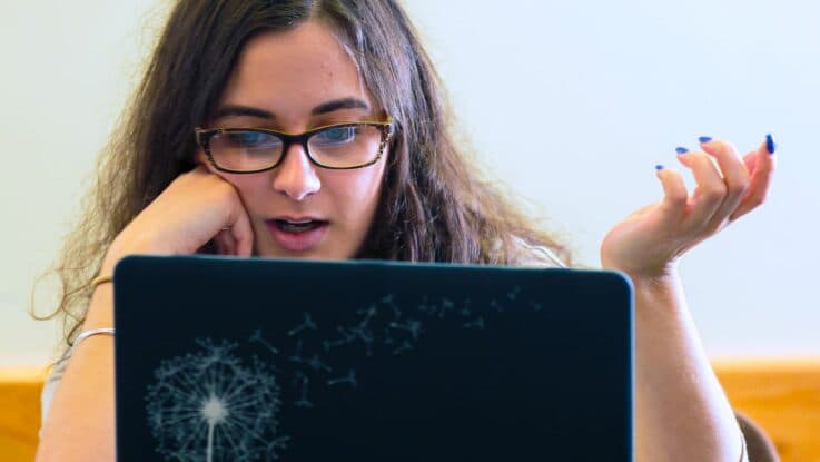 a student looks at information on her laptop with a surprised look on her face