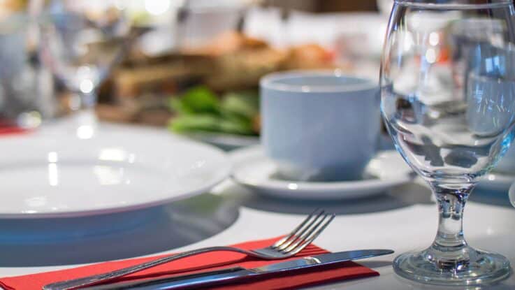 A table setting with plate, utensils, cup, and glassware