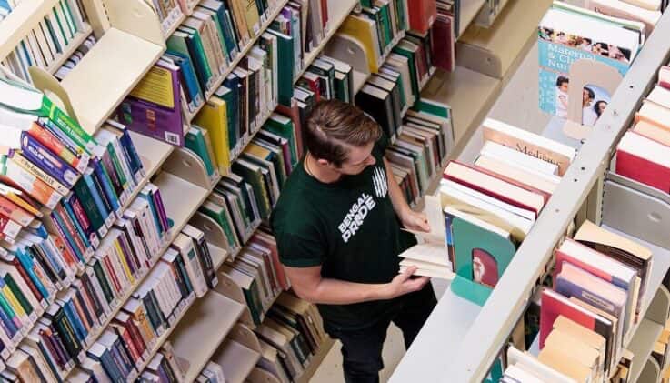 UMFK student in the library stacks