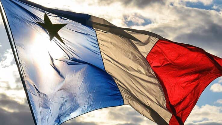 acadian flag flying in the wind as the sun shines through the fabric