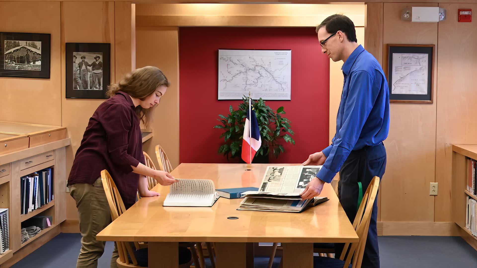 Acadian Archives Director Patrick Lacroix and Archivist Madeline Soucie stand around a table in the reading area of the archives