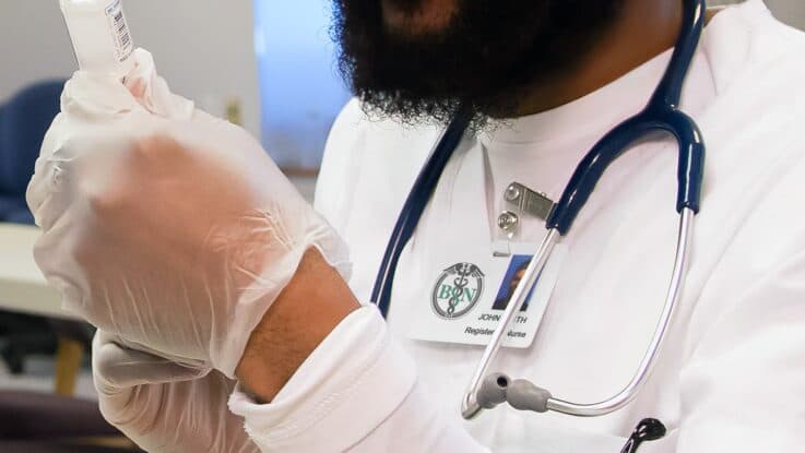 a nurse holds a syringe as he fills it with medicine