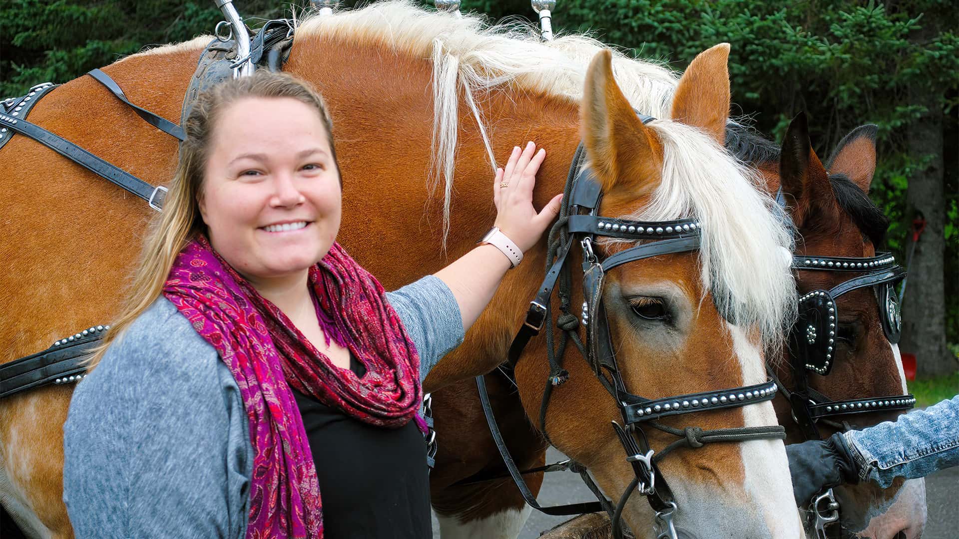 a female UMFK alum stands beside some horses during an event