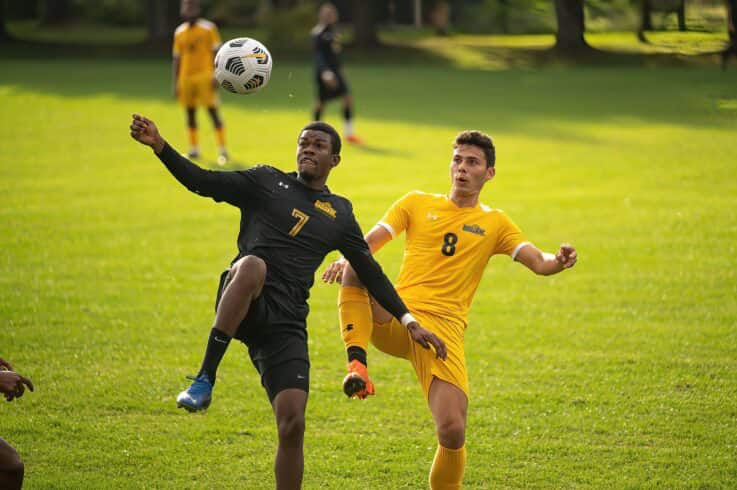 two athletes compete for a soccer ball in the air
