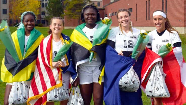 female international soccer players pose with their nation's flags