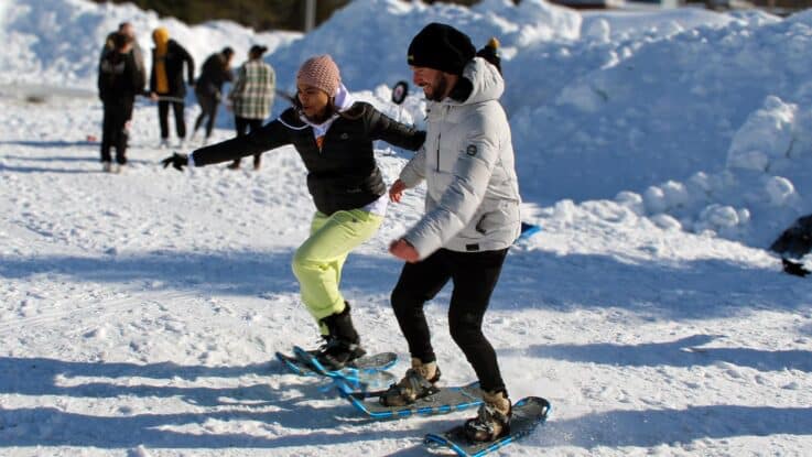 two students, a male and a female, race on snowshoes during a winter carnival