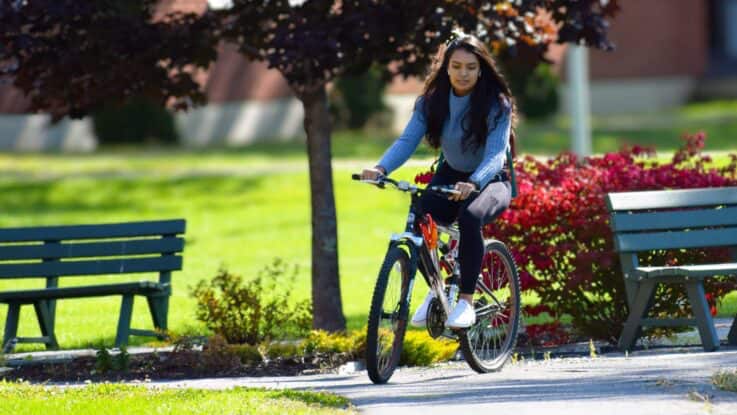a female student bikes across campus as she heads to class