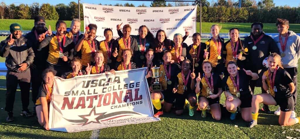 The 2022 UMFK Women’s Soccer team pose with their championship banner and trophy