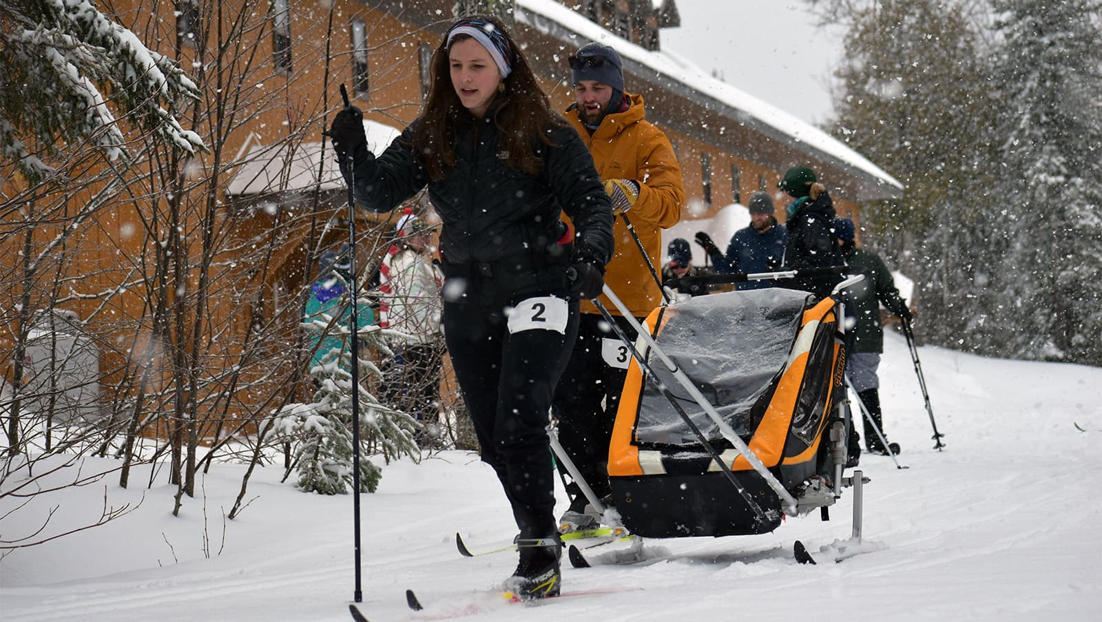 a female cross-country skier tows a sled behind her