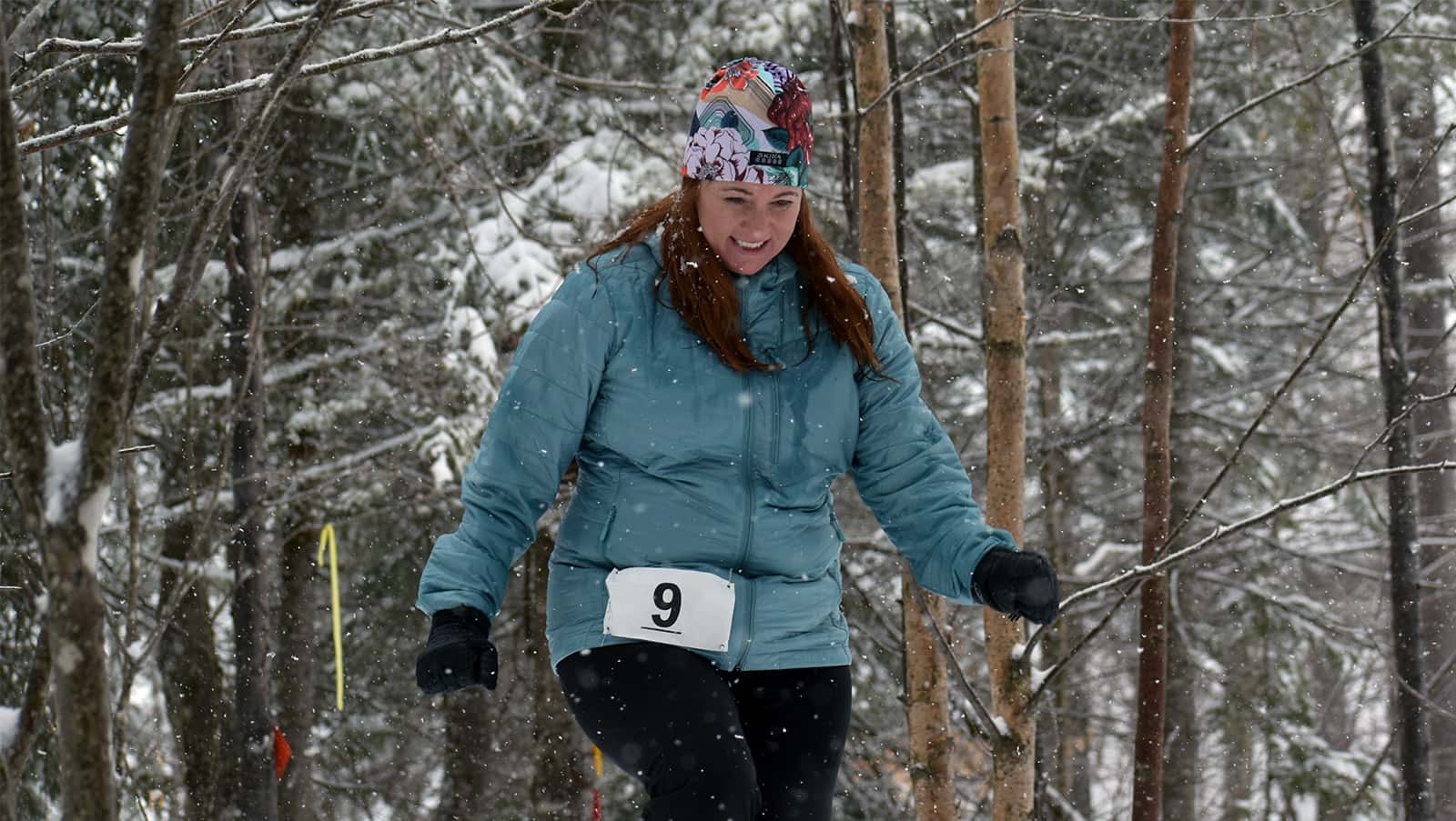 a female participant smiles as she snowshoes along the trail