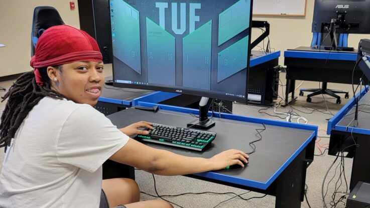 a UMFK student sits at one of the eSports Center gaming computers while looking at the camera