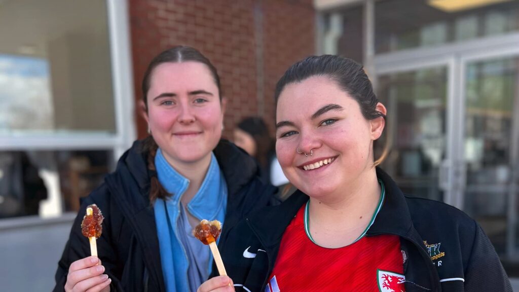 Two female students enjoy maple taffy during the UMFK Sucrerie.