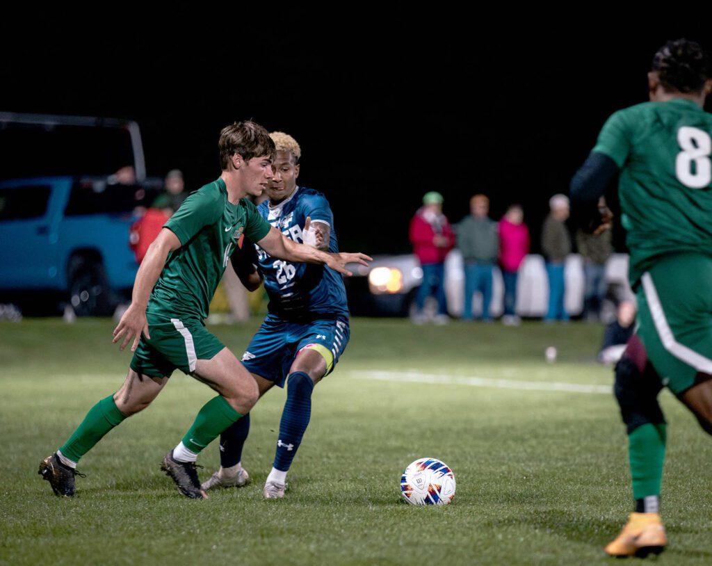 male soccer players scramble for control of the ball