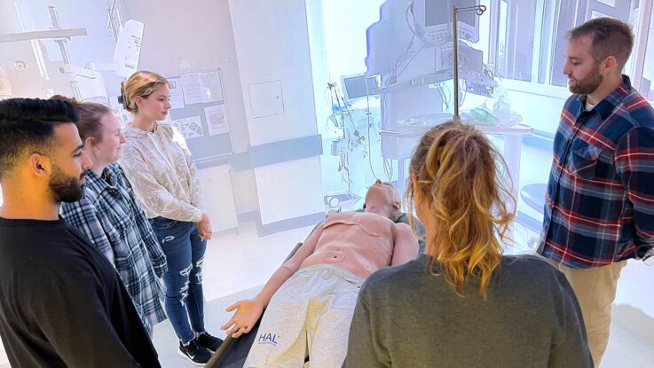 nursing students gather around a virtual patient in a nursing simulation