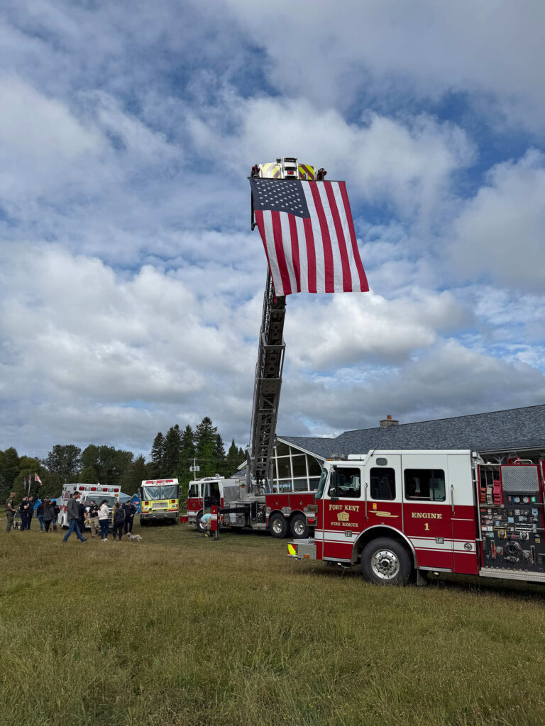 an American flag hangs from the ladder of a fire truck